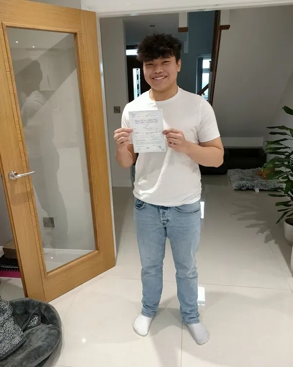 Successful learner holding their driving test pass certificate