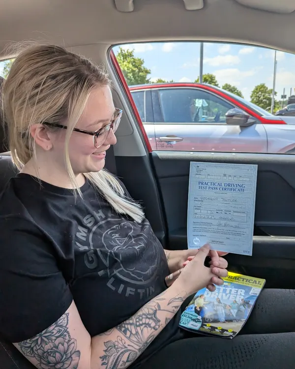 Learner celebrating a driving test pass beside the tuition car