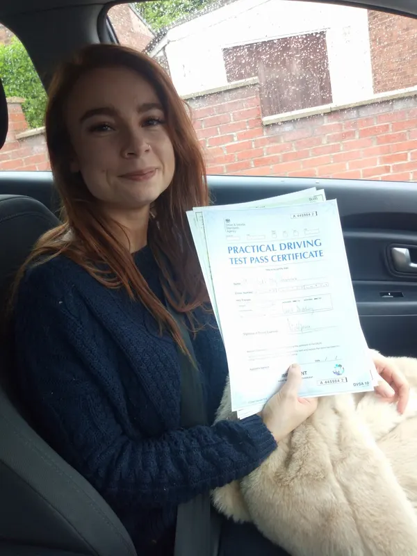 Learner holding their driving test pass certificate with a smile